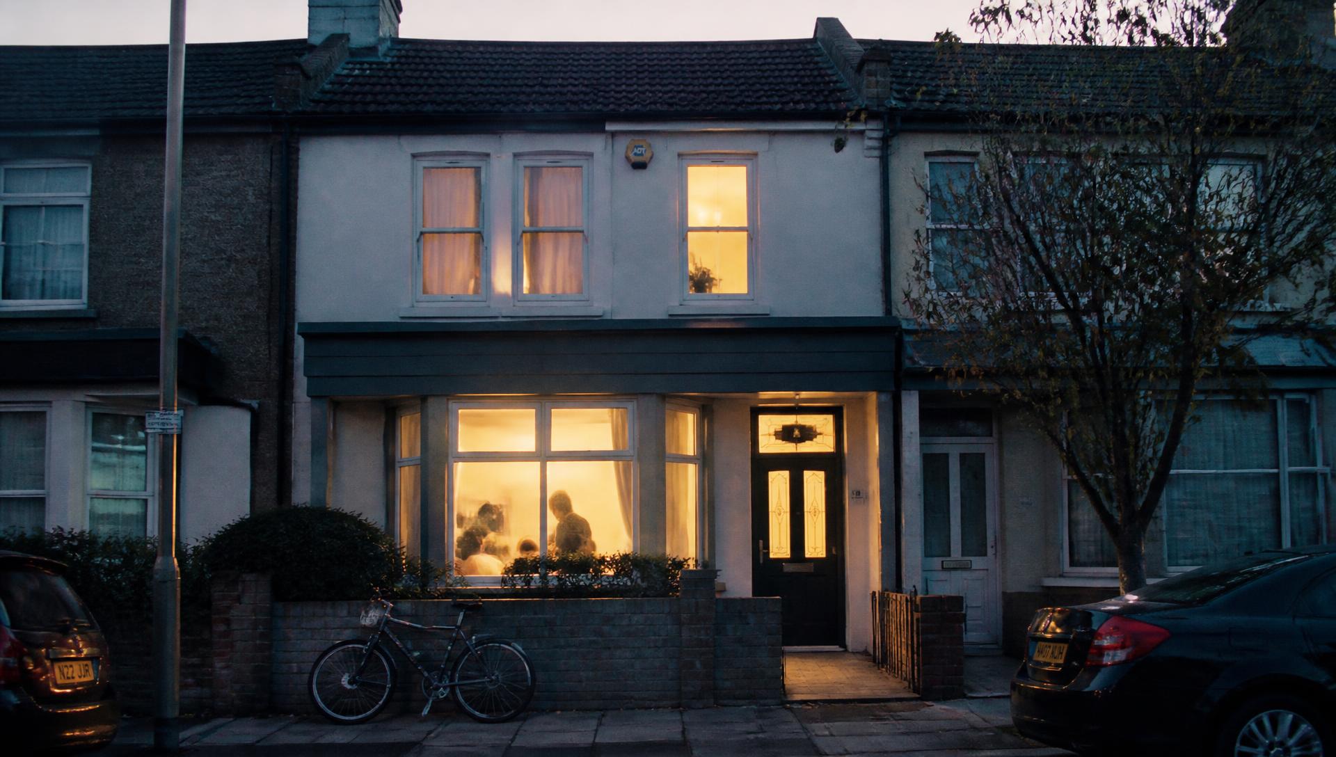 A modest terraced family home at dusk with warm light inside